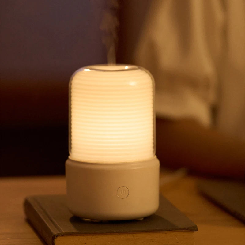 Beige aroma diffuser with glowing light on a book, perfect for relaxation.

