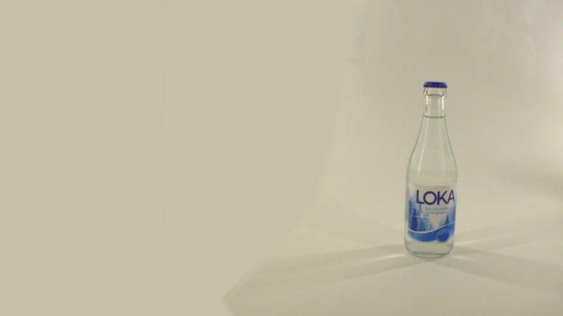 A bottle of water being opened with a smart tool in a modern interior